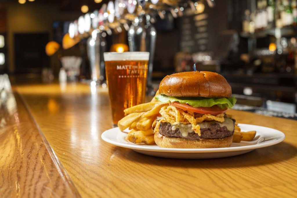 Matt the Miller’s burger garnished with fried onions and served with French fries and glass of draft beer