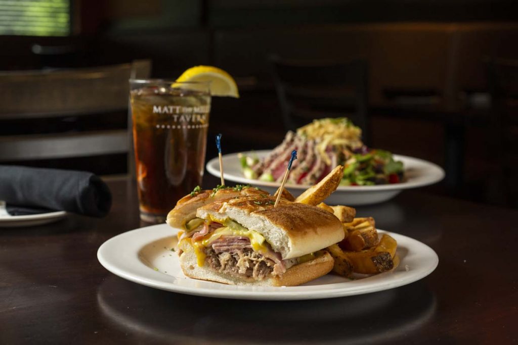 Grilled Cuban sandwich with French fries and glass of iced tea garnished with lemon wedge