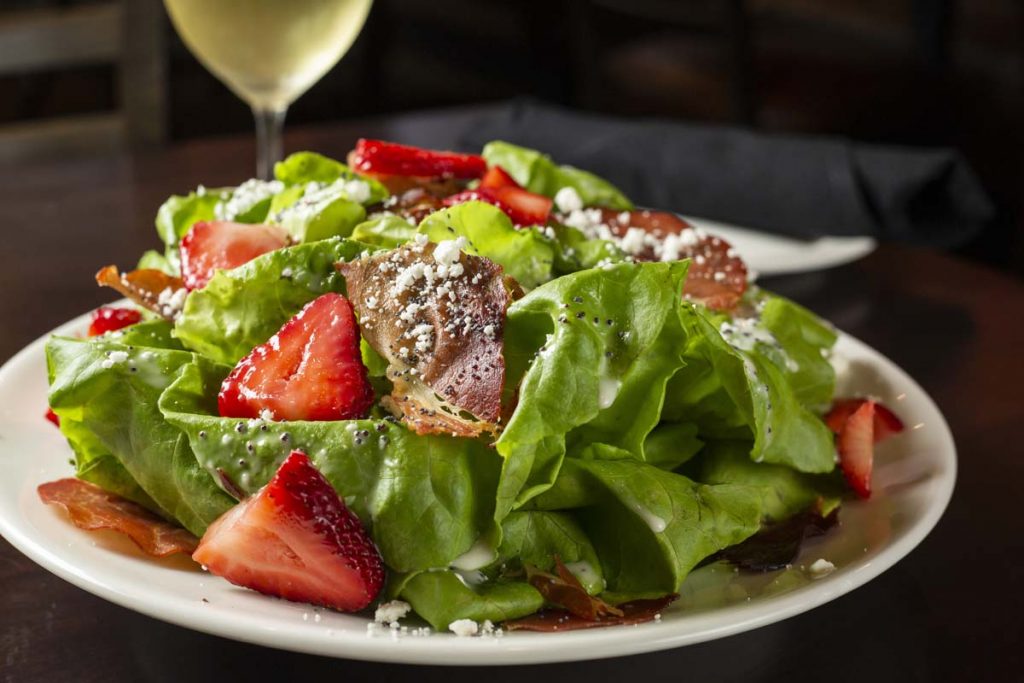 Bibb lettuce salad with strawberries and glass of white wine