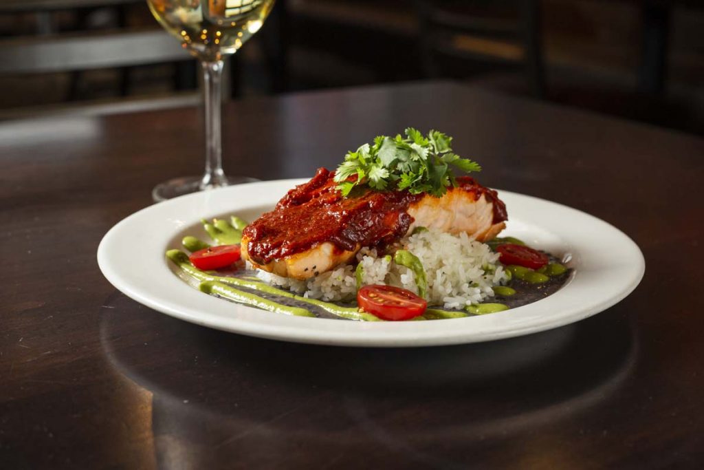 Plated Baja Salmon dish with sauce and white wine