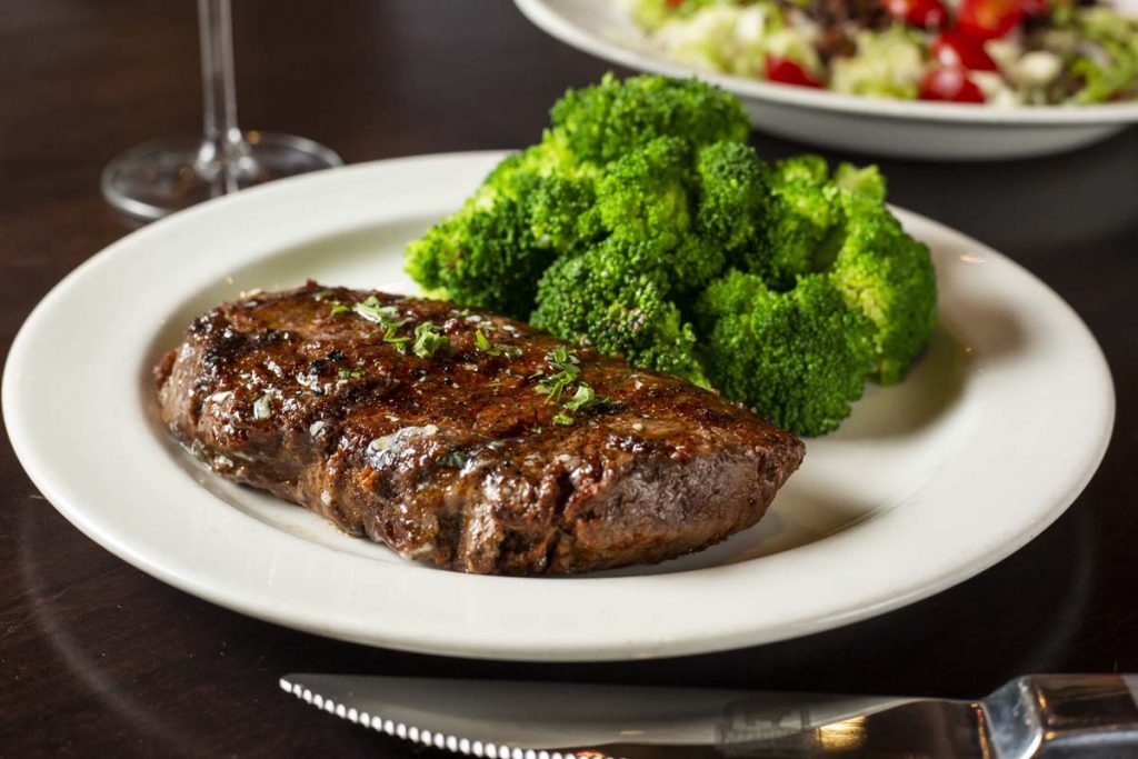 Plated sirloin steak with broccoli and glass of wine