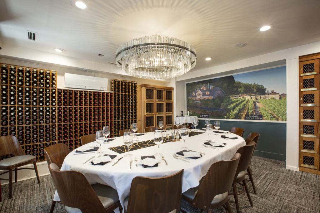 Private dining room with wine cellar on one wall and service set for 12 on center table