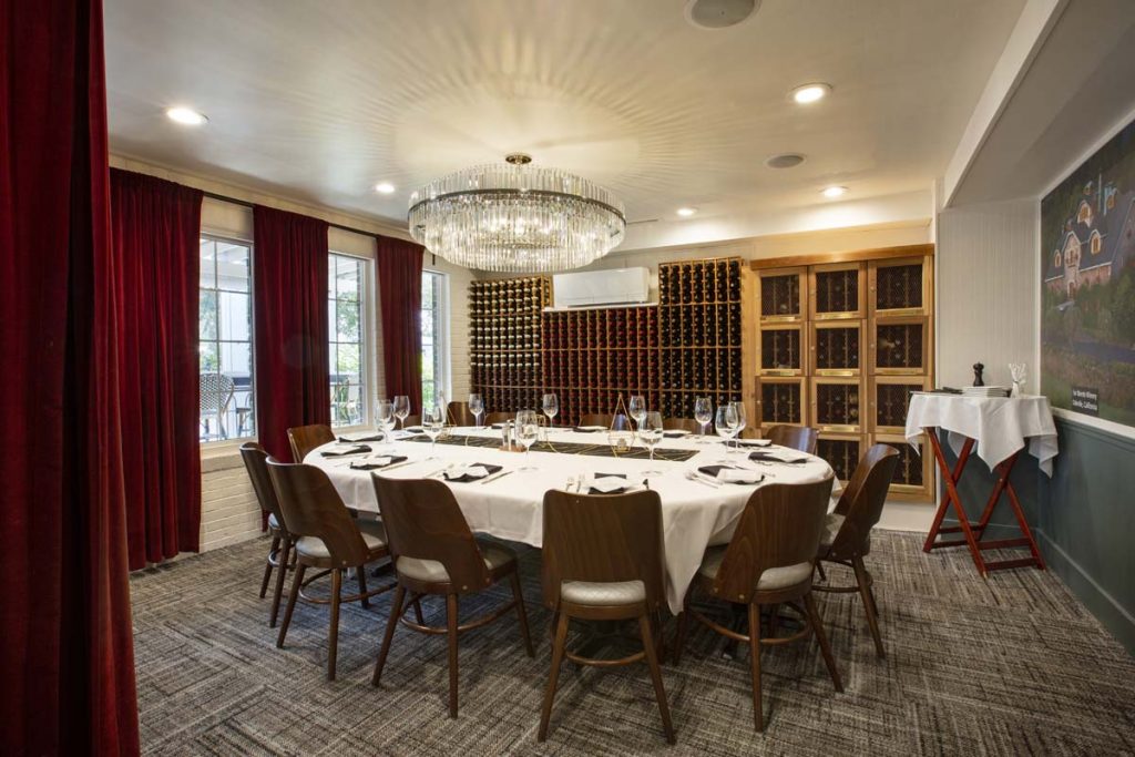 Private dining room with wine cellar on one wall and service set for 12 on center table