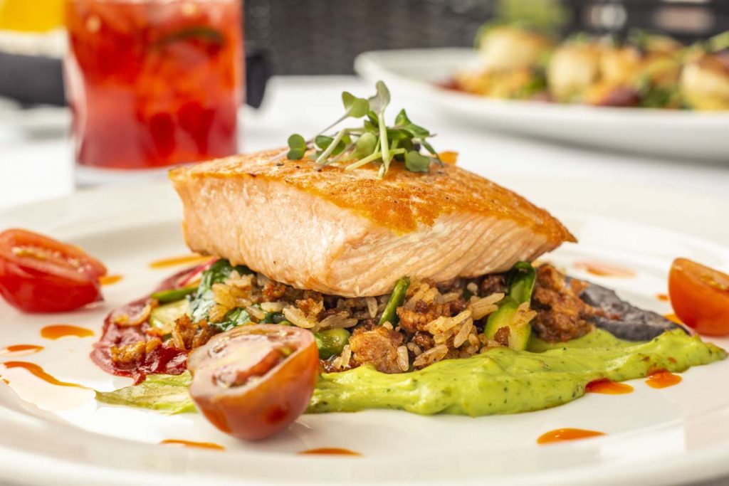 Tucci’s pan-seared salmon on bed of wild rice with cocktail in background