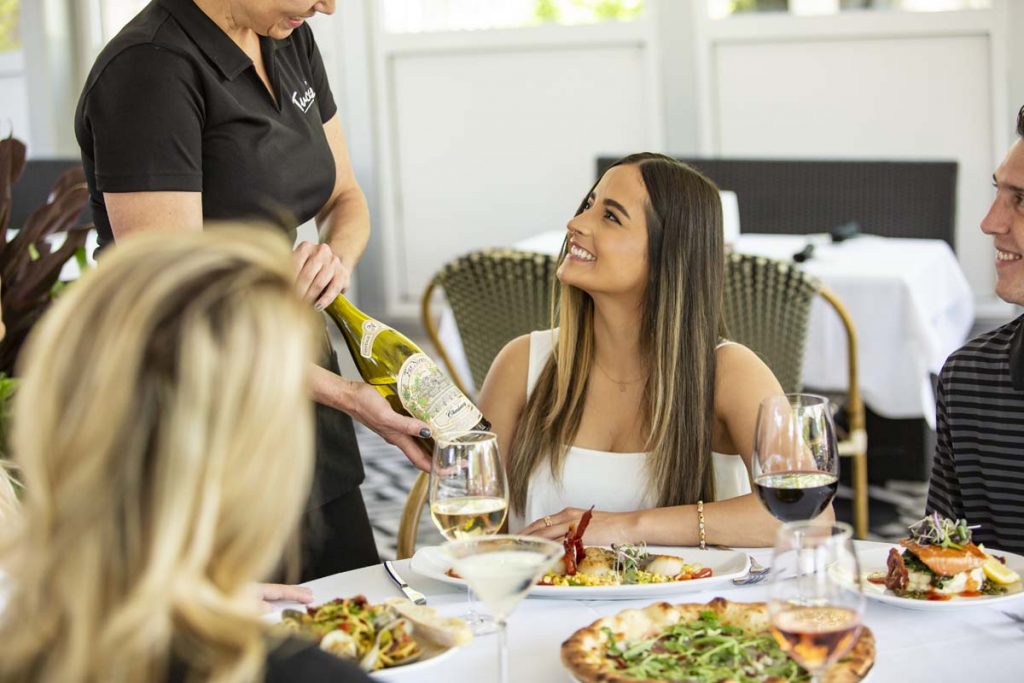 Female guest smiles as wine is presented by server